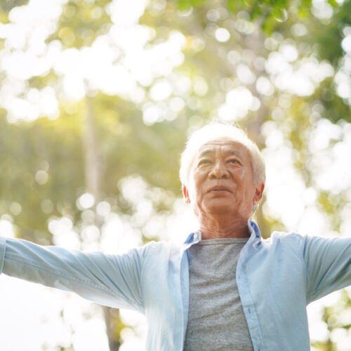 asian old man enjoying fresh air in park senior asian man enjoying fresh air walking with open arms outdoors in park
